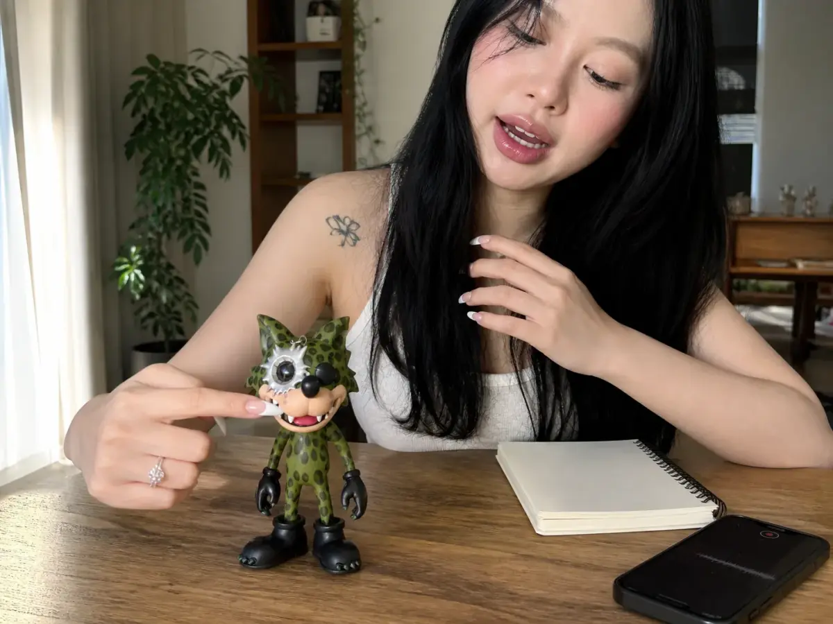 Creator pressing a small green hard-shell WOWNNY collectible while recording a voice note